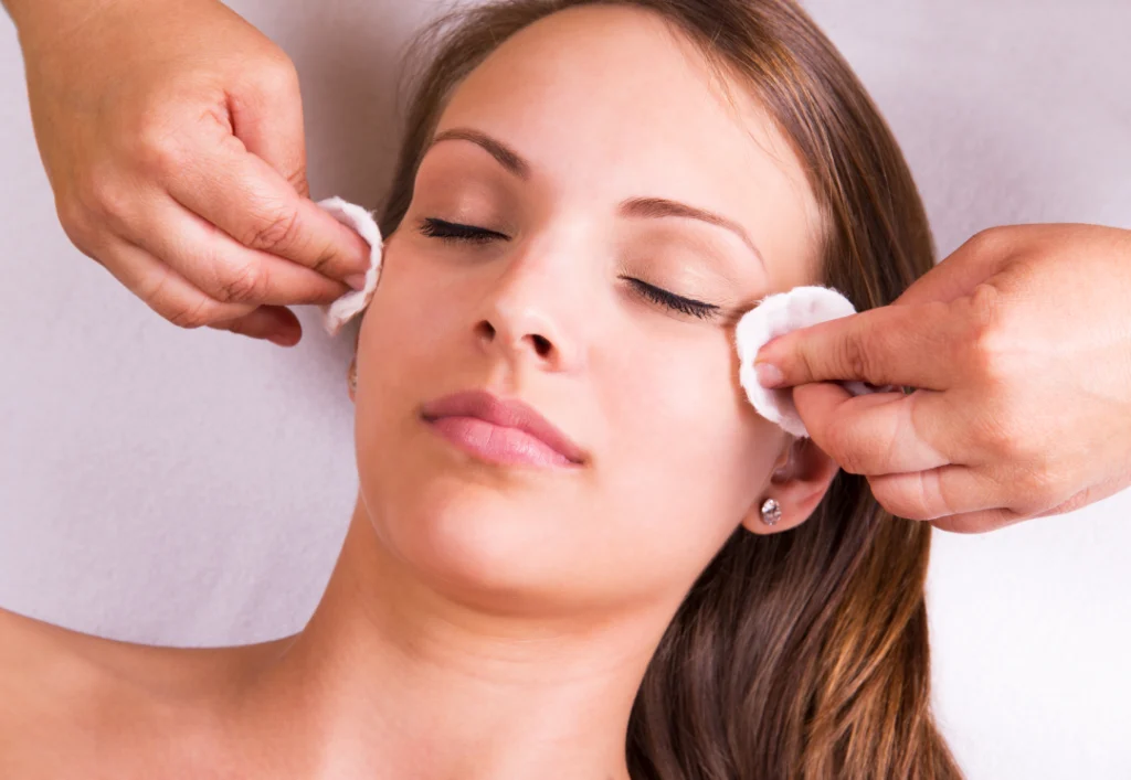 A client relaxes during a HydraFacial treatment while a professional gently massages and hydrates their face.