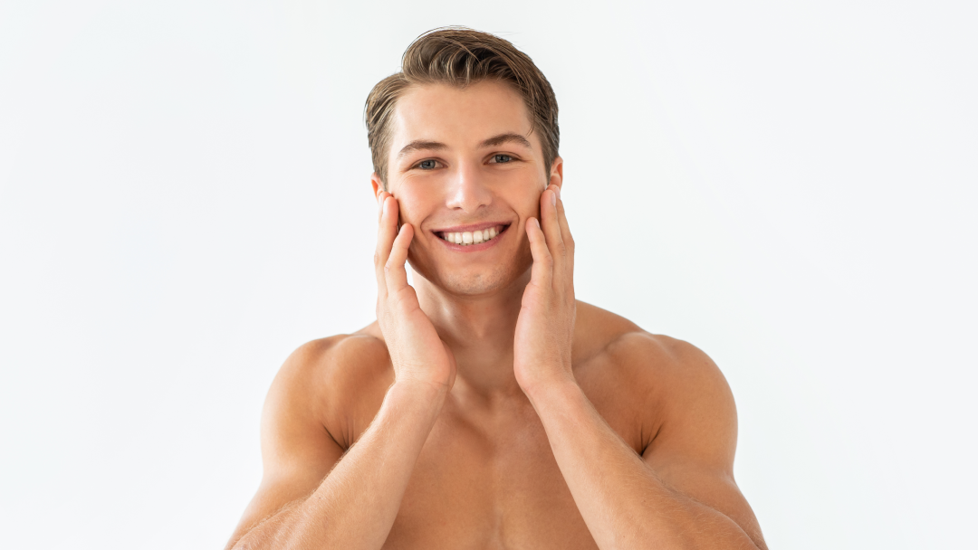 A man smiles while touching his smooth, glowing skin after undergoing fractional laser treatment.