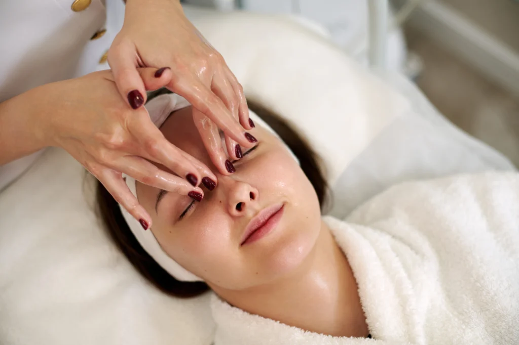 A person receives gentle facial cleansing with cotton pads as part of a HydraFacial preparation process.